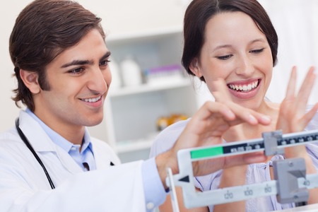 male doctor weighing happy female patient